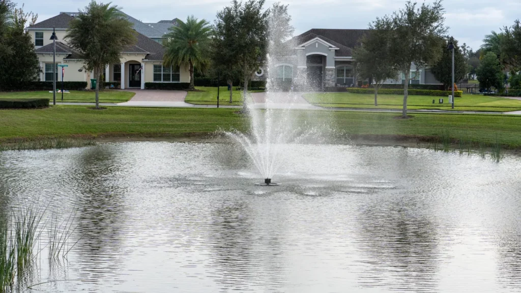 Fountain in a pond in front of homes at Hickory Hammock